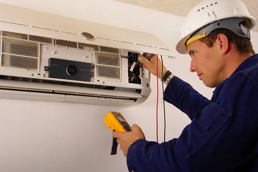 Profesional comprobando la electricidad de un acondicionador de aire con un multímetro