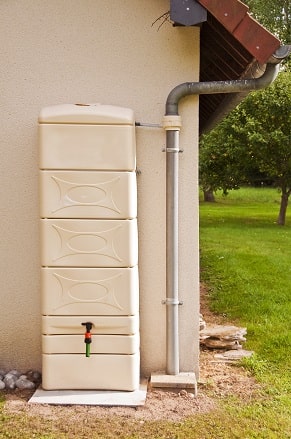 Récupérateur d'eau fixé à un mur derrière une maison