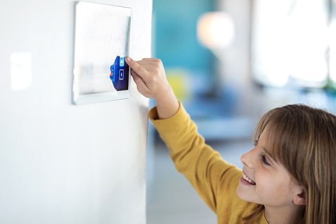 Jeune fille utilisant une tablette pour contrôler un système domotique