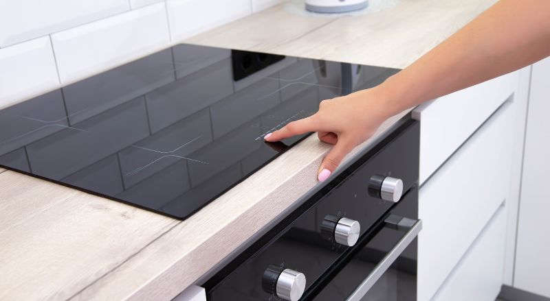 Doigt pose sur le bandeau de commande d une plaque a induction