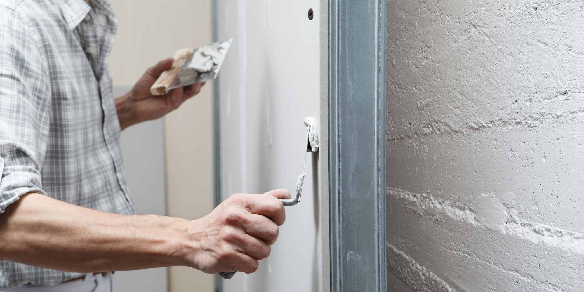 personne en train d'appliquer un enduit de lissage sur un mur