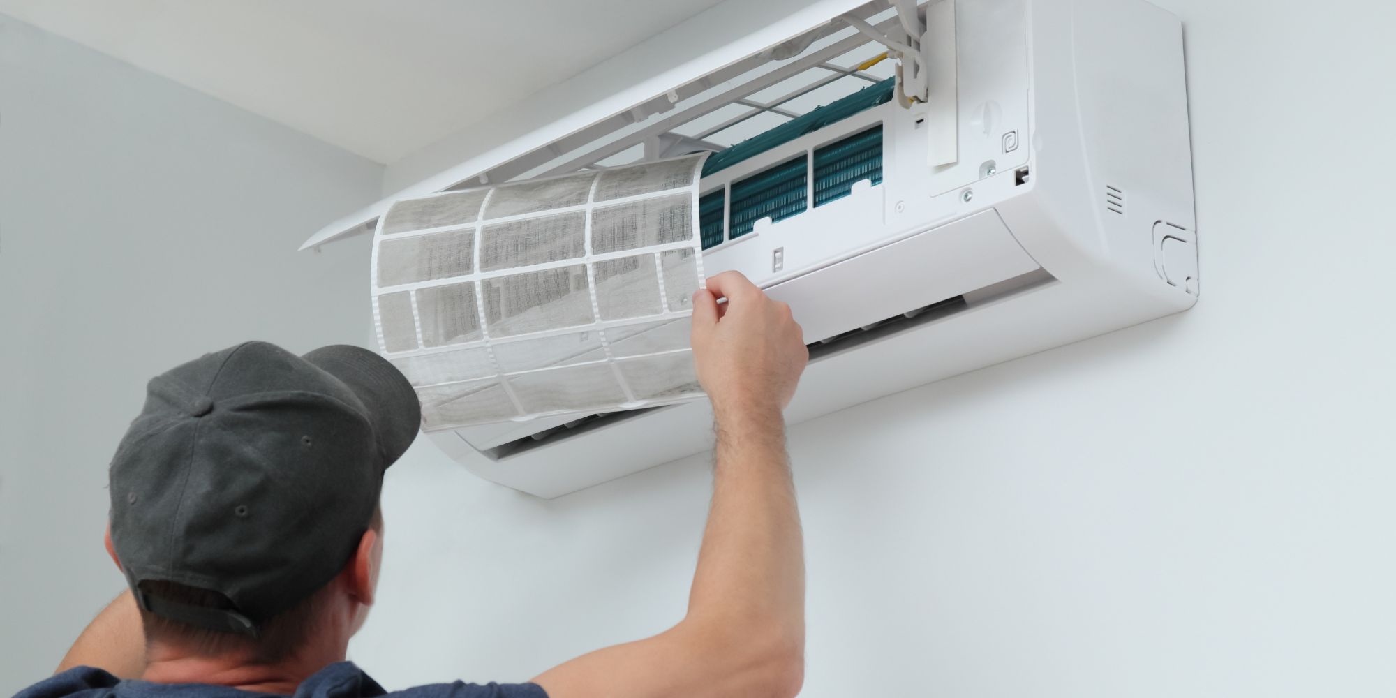 Professionnel en train de remettre en place les filtres sur une unité murale, pour illustrer le concept du prix pour l'entretien d'une climatisation.