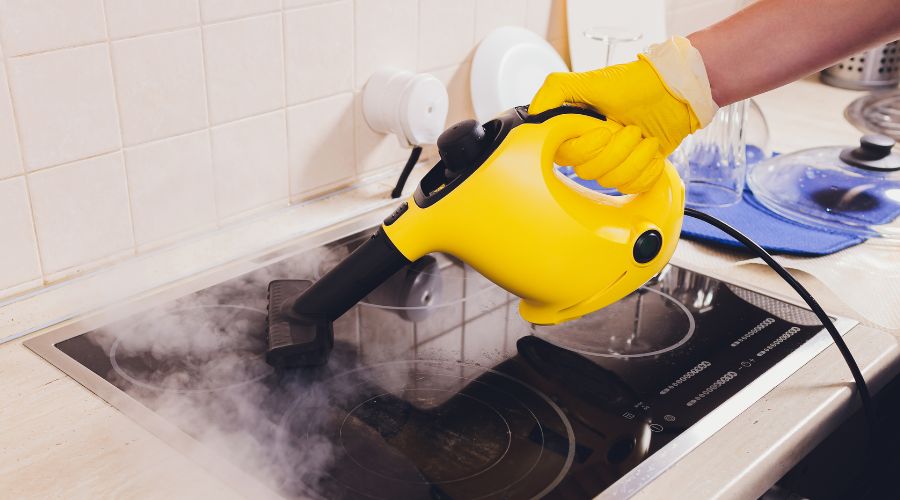 Femme qui nettoie sa plaque de cuisson avec un nettoyeur vapeur