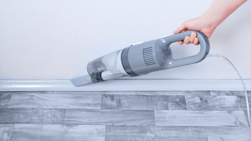 Personne qui passe l'aspirateur sur les plinthes