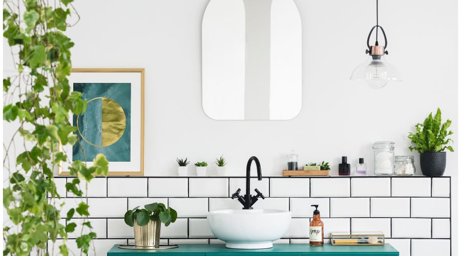 salle de bain avec muret adosse au mur et contrelequel est fixe un meuble vasque le muret permet de pososer des accessoires de toilettes et des objets decoratifs il est surmonte d un miroir ovale et d un luminaire suspendu original