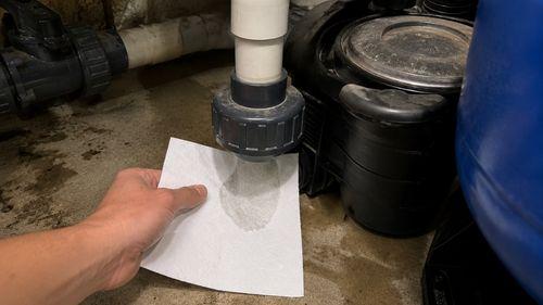 Inspection d'un raccord PVC de piscine avec papier absorbant pour détecter et réparer une fuite de piscine en mode filtration