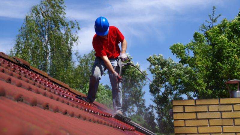 Professionnel en train de nettoyer et de démousser une toiture