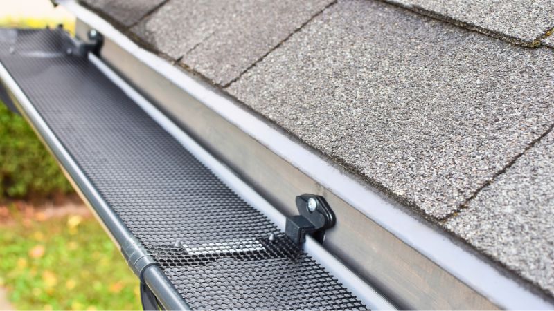 Grille noire installée sur une gouttière pour limiter le dépôt de feuilles et ainsi réduire l'entretien d'une gouttière