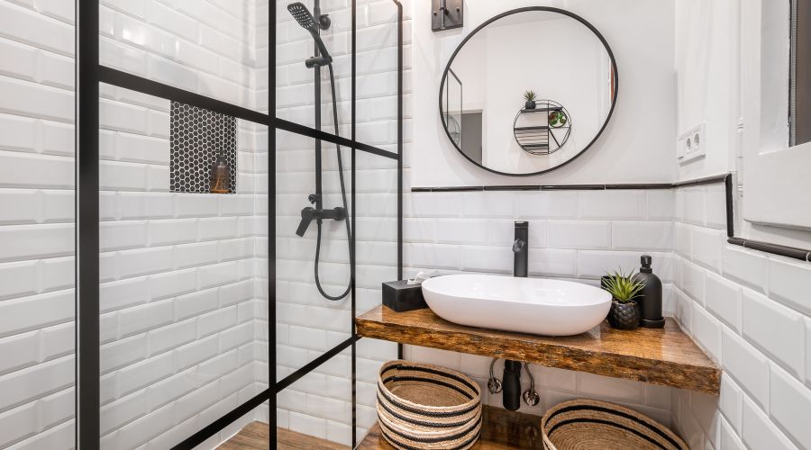 salle de bain rectangulaire moderne avec mur blanc et credence douche en carrelage blanc miroir rond et vasque pose sur un plan de travail en bois