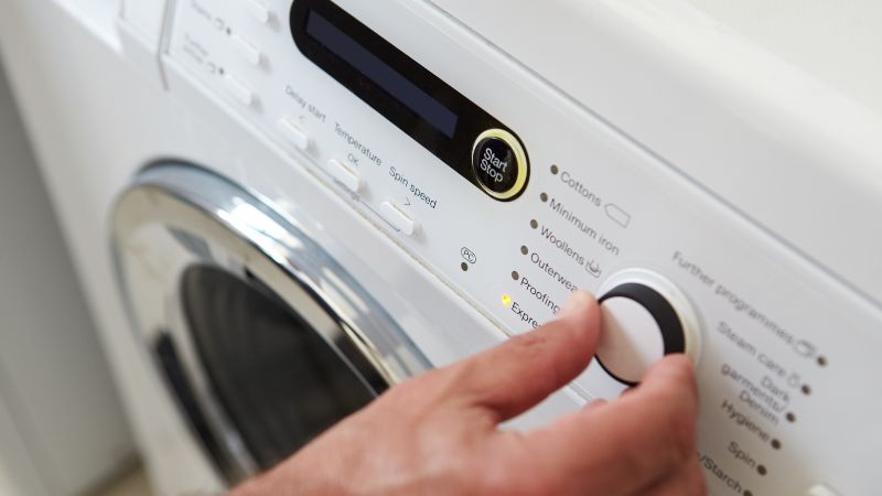 gros plan d un homme choisissant le programme de cycle sur la machine a laver