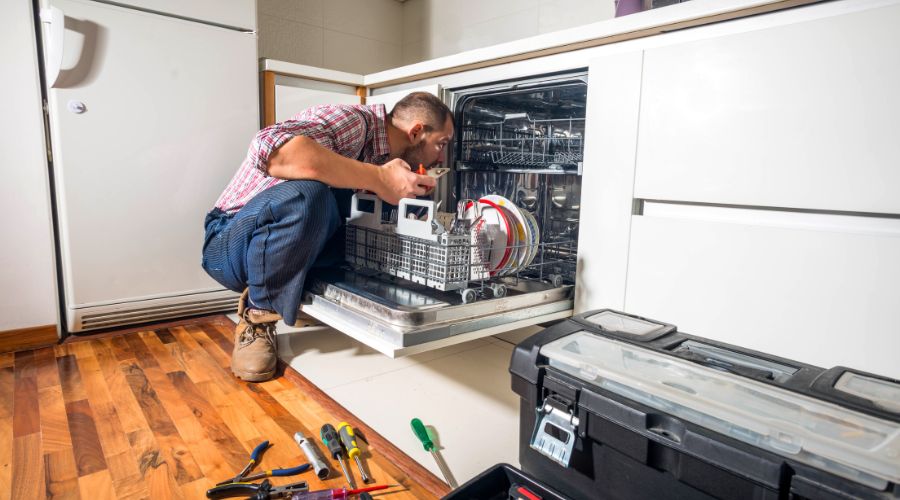 un reparateur examine l interieur de la cuve du lave vaisselle en dessous du panier inferieur la ou se situe l element chauffant
