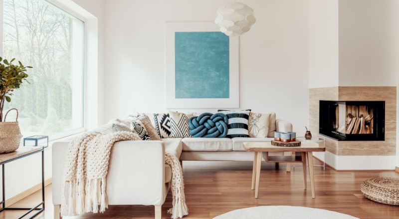 coussin noeud bleu turquoise sur un canape d angle beige et affiche abstraite sur un mur blanc dans un interieur de salon moderne avec parquet flottant teinte rosee