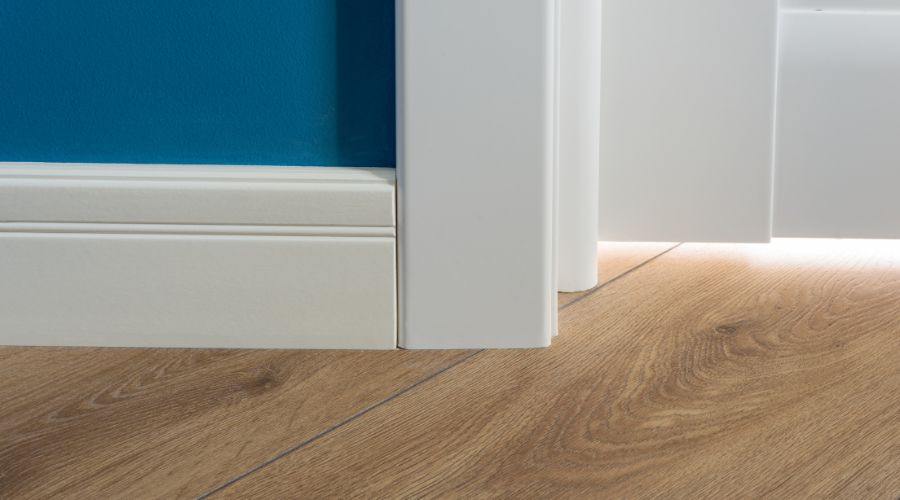 details d un interieur avec finitions parfaites parquet stratifie imitant la texture du chene plinthes blanches porte blanche mur bleu