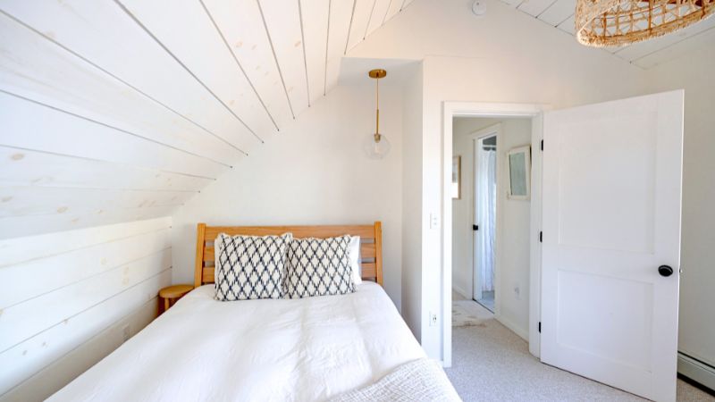 Chambre avec mur en lambris blanc – apparence impeccable – pourtant, l’origine d’une infestation de punaise de lit peut se cacher dans les plinthes, le sommier, les lambris ou les fissures invisibles autour du lit