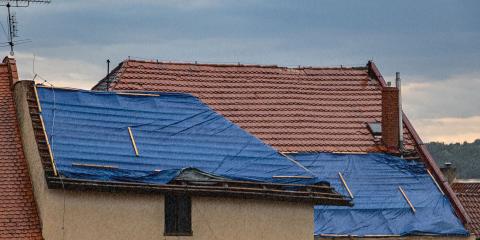 Bâche anti-pluie bleue installée sur tout un pan de toiture en tuiles