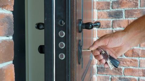 un homme insere sa cle dans la serrure de sa porte blindee pour rentrer 