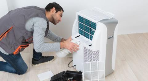 Climaticien positionnant une gaine d evacuation sur un climatiseur mobile