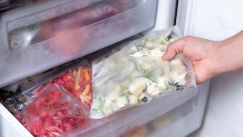 une personne prenant un sachet de legumes congeles du congelateur 