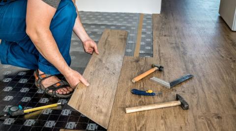 professionnel posant un revetement de sol en stratifie ou parquet massif lors d une renovation 