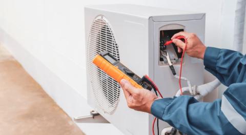 professionnel testant une unite de pompe a chaleur installee en exterieur