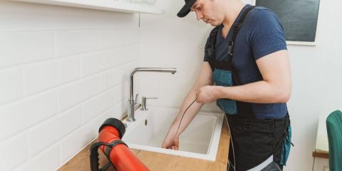 Plombier utilisant un long furet déboucheur pour intervenir sur un lavabo