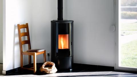 Poele noir moderne avec flammes et sac a granules dans un salon