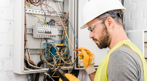 électricien qui contrôle un tableau électrique 