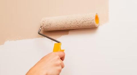 personne qui applique de la peinture sur du papier peint