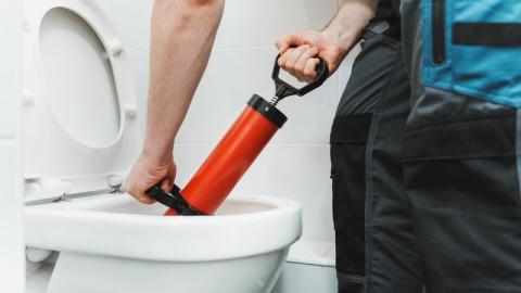 plombier debouchant des toilettes avec une pompe 