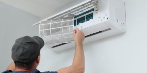 Professionnel en train de remettre en place les filtres sur une unité murale, pour illustrer le concept du prix pour l'entretien d'une climatisation.