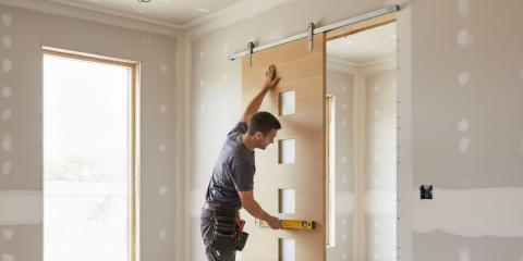 Menuisier qui pose une porte coulissante à galandage en rénovation