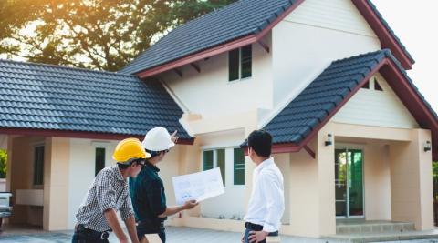 deux architectes et un proprietaire discutent et planifient les travaux de renovation devant une maison