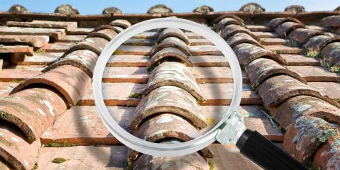 Une loupe devant une toiture en tuiles, pour symboliser la recherche de fuite sur toiture