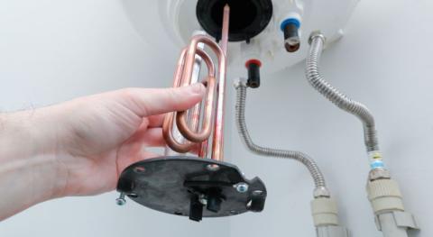 main d homme en gros plan changeant une resistance de chauffe eau lors d une maintenance 