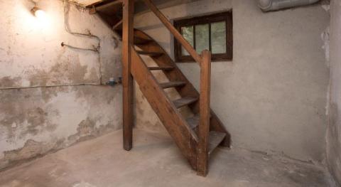 sous sol vide dans une vieille maison avec un peu de lumiere et un escalier en bois